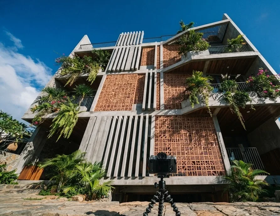 Camera on a tripod photographing a facade of concrete fins and brick lattice screens