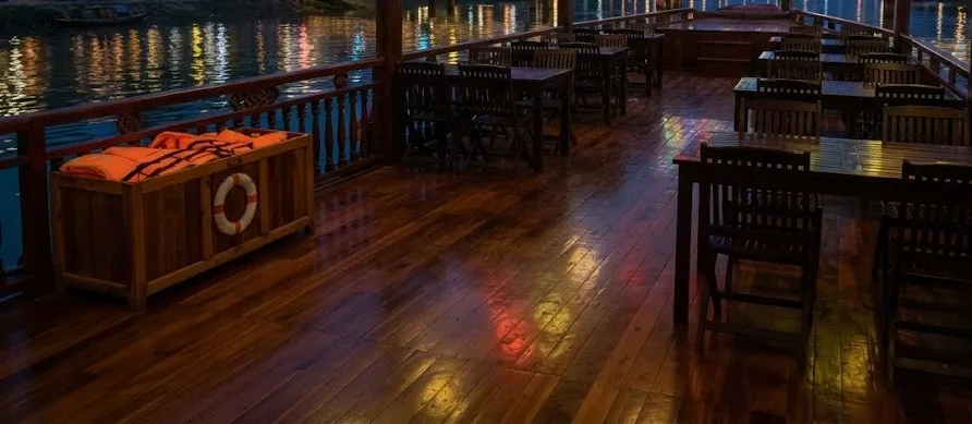 Upper deck of a river cruise boat at night with tables and a box of life vests