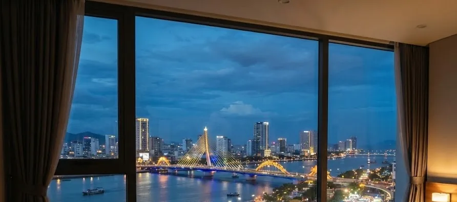 Hotel room window overlooking the river, lit bridges and city lights at dusk