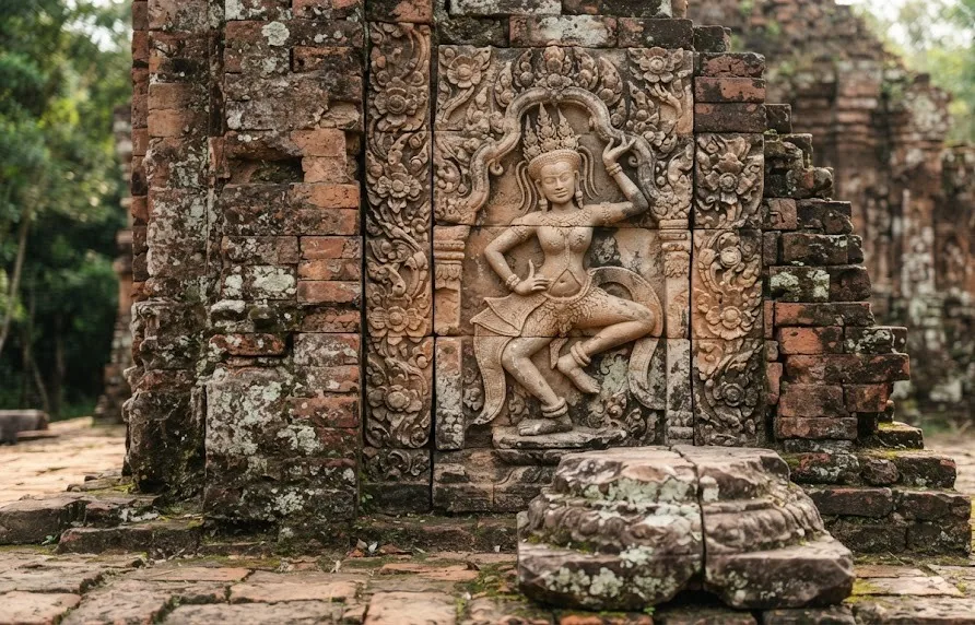 Carved sandstone dancer relief set in weathered red brick with floral motifs and a pedestal