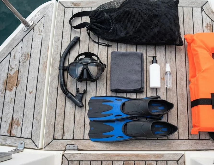 Snorkeling gear on a boat deck: mask, snorkel, fins, towel and life vest