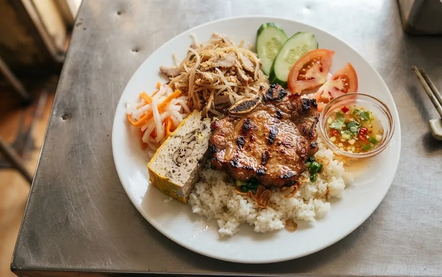 Broken rice plate with grilled pork chop, shredded pork skin, steamed egg loaf, pickles and dipping sauce