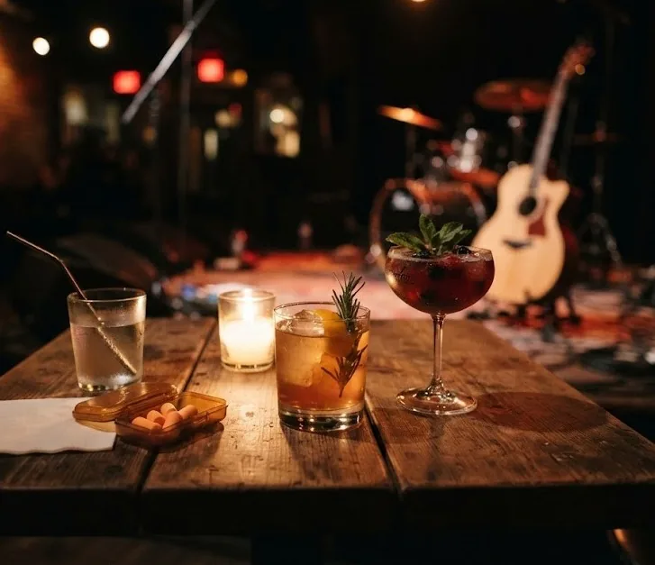 Cocktails, candle and earplugs on a bar table in front of a live music stage