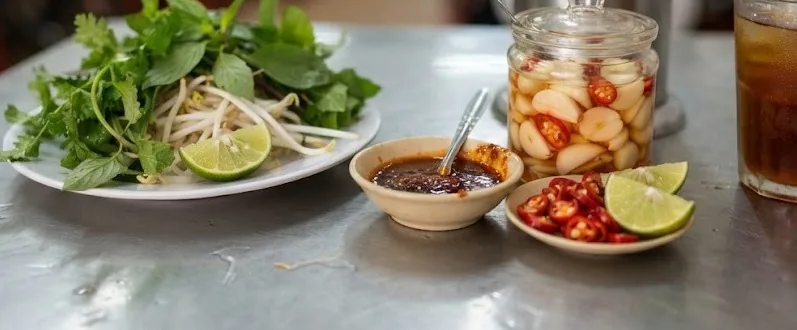 Noodle shop condiments with herbs, pickled garlic, chili sauce and lime