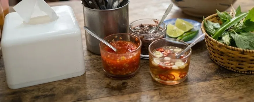Noodle shop condiments: chili sauce, shrimp paste, fish sauce with chili, lime and herbs