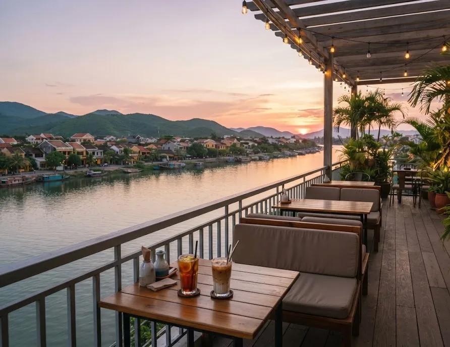 Riverside cafe terrace with string lights and iced drinks at sunset