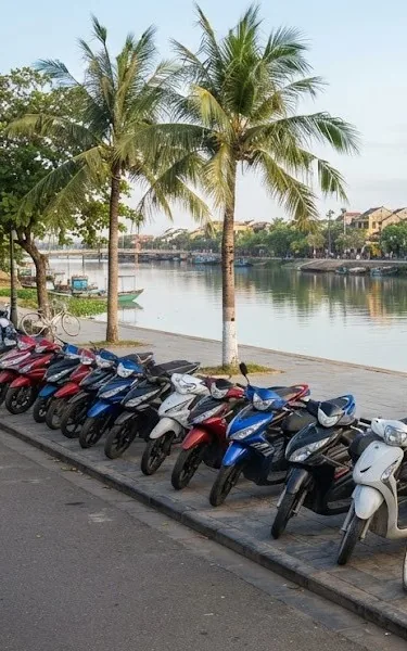 Row of rental scooters and bicycles parked along a riverside promenade