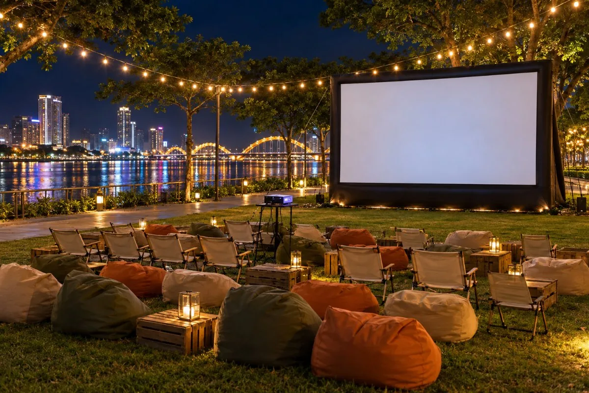 Pop up outdoor cinema with beanbags, chairs and an inflatable screen by the river at night