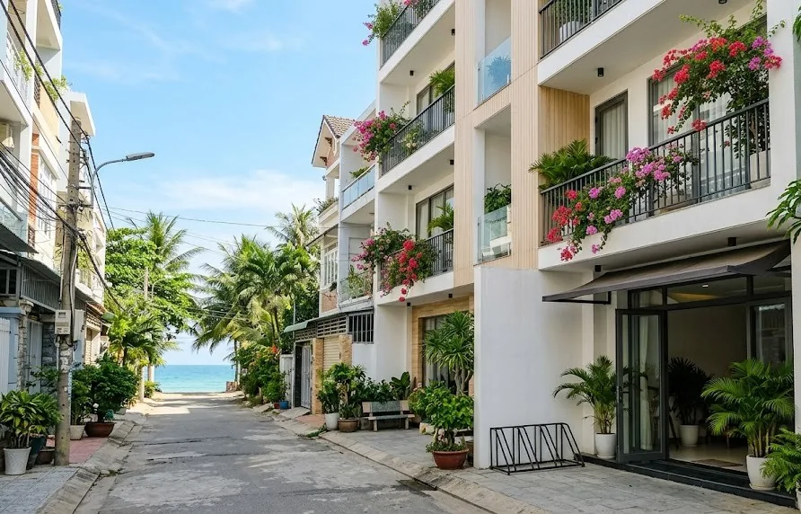Small white boutique hotel with flower balconies on a quiet street leading to the beach