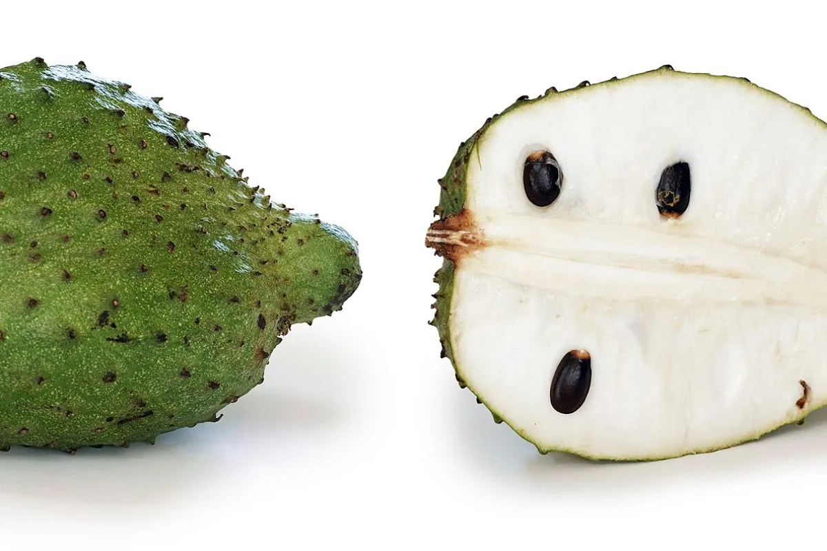 A soursop cut open to show the white flesh and black seeds
