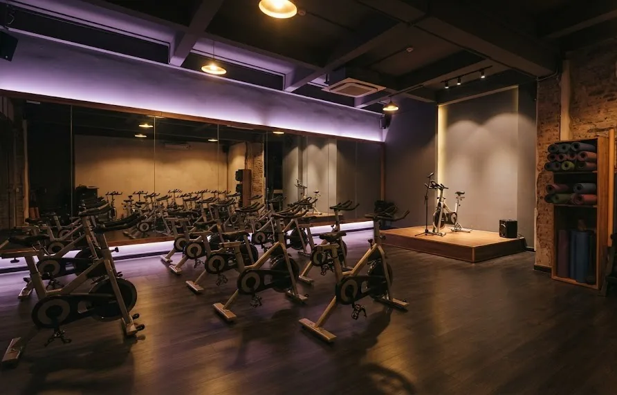 Boutique studio with rows of spin bikes, a small stage, mirrors and a rack of yoga mats